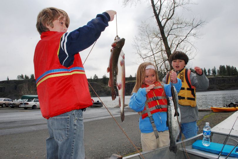 Kids pose for photos with trout caught opening day at Badger Lake. (Rich Landers)