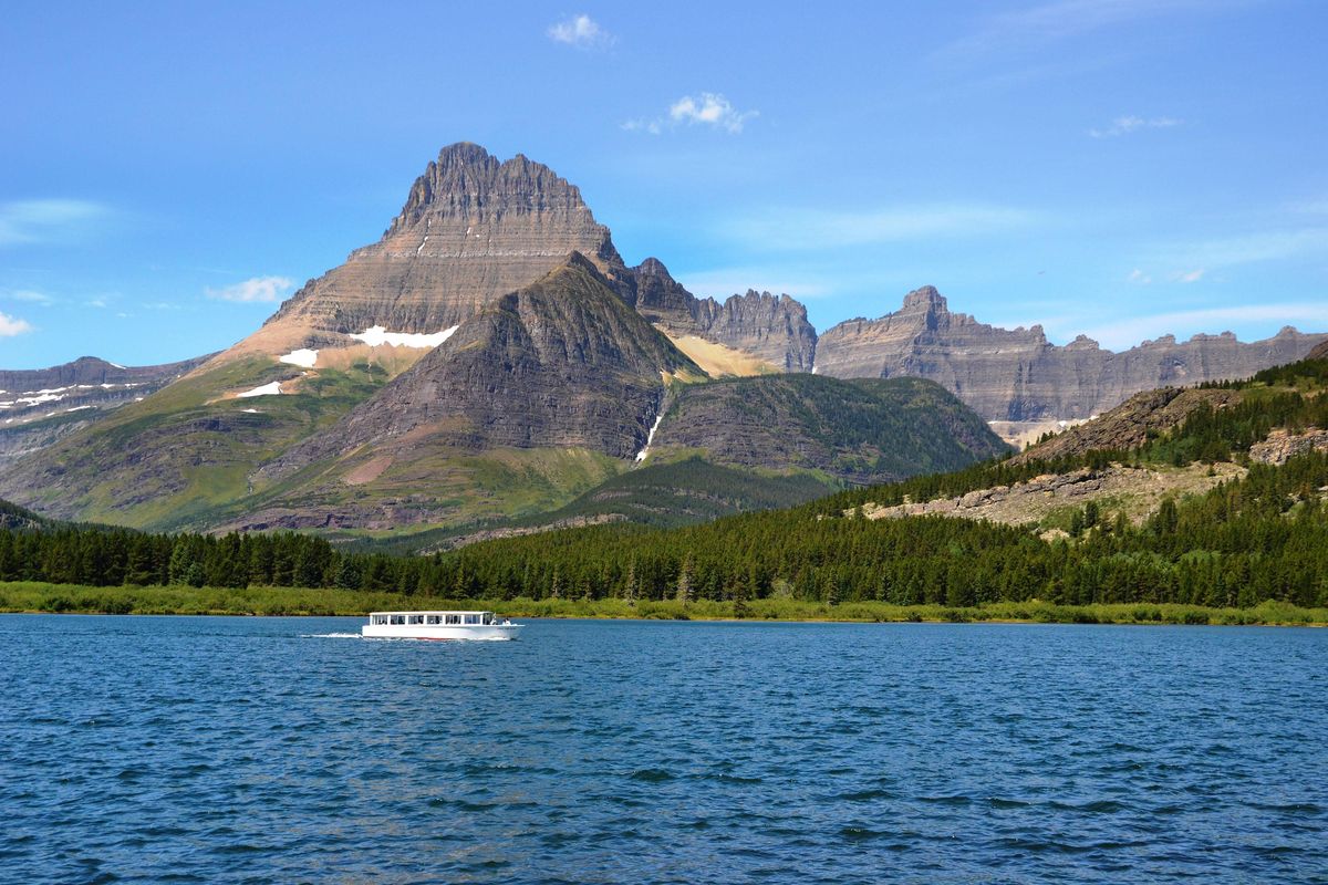 Many Glacier Boat: The cruise boat Chief Two Guns on Swift Current Lake in the Many Glacier area is dwarfed by the dramatic mountain setting. (SR)