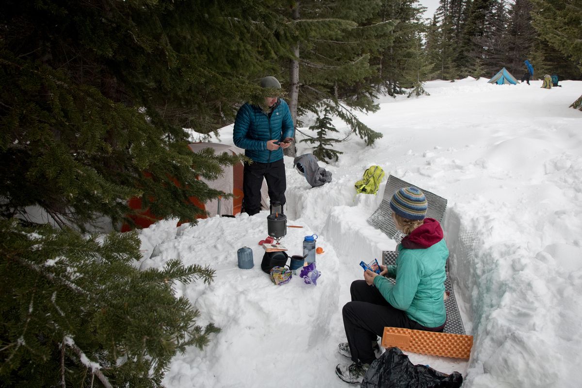 Will Holmquist, left, and Carolyn Cartwright sit in the "kitchen" they built while snow camping in March 2018 with the Spokane Mountaineers. (Eli Francovich / The Spokesman-Review)