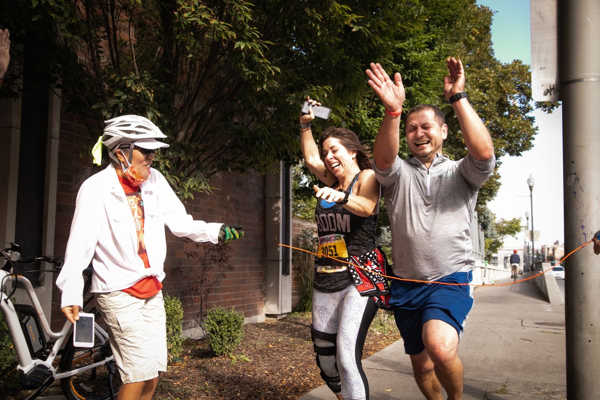 Runners Nadine Burgess and Alex Dratch spring for a photo finish during Virtual Bloomsday while Kiyomi Walker (left) and Gloria Castellaw (not pictured) cheer them on with a makeshift finish line cord on Sunday in Spokane.  (Libby Kamrowski/ THE SPOKESMAN-REVIEW)