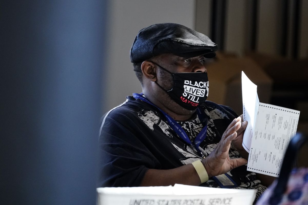 An election worker holds a ballot during vote counting in the general election, Nov. 4 at State Farm Arena in Atlanta. President-elect Joe Biden won in Michigan, Wisconsin, Pennsylvania and Georgia because of Black voters, many of them concentrated in big cities.  (Brynn Anderson)