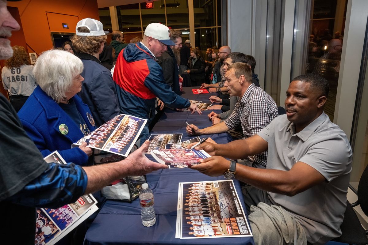 Former Gonzaga basketball players Quentin Hall, on far right, and Casey Calvary autograph team photos at the Northwest Passages 25th anniversary reunion of the 1999 Elite Eight team on Friday at the Myrtle Woldson Performing Arts Center.  (COLIN MULVANY/THE SPOKESMAN-REVIEW)