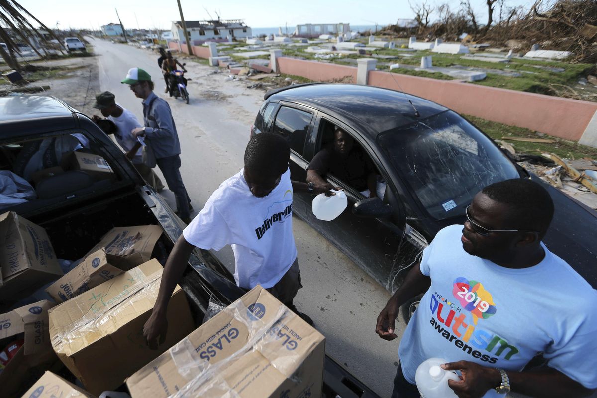 Volunteers handout food and water to the survivors of Hurricane Dorian in Marsh Harbor, Abaco Island, Bahamas, Friday, Sept. 6, 2019. The Bahamian health ministry said helicopters and boats are on the way to help people in affected areas, though officials warned of delays because of severe flooding and limited access. (Fernando Llano / Associated Press)