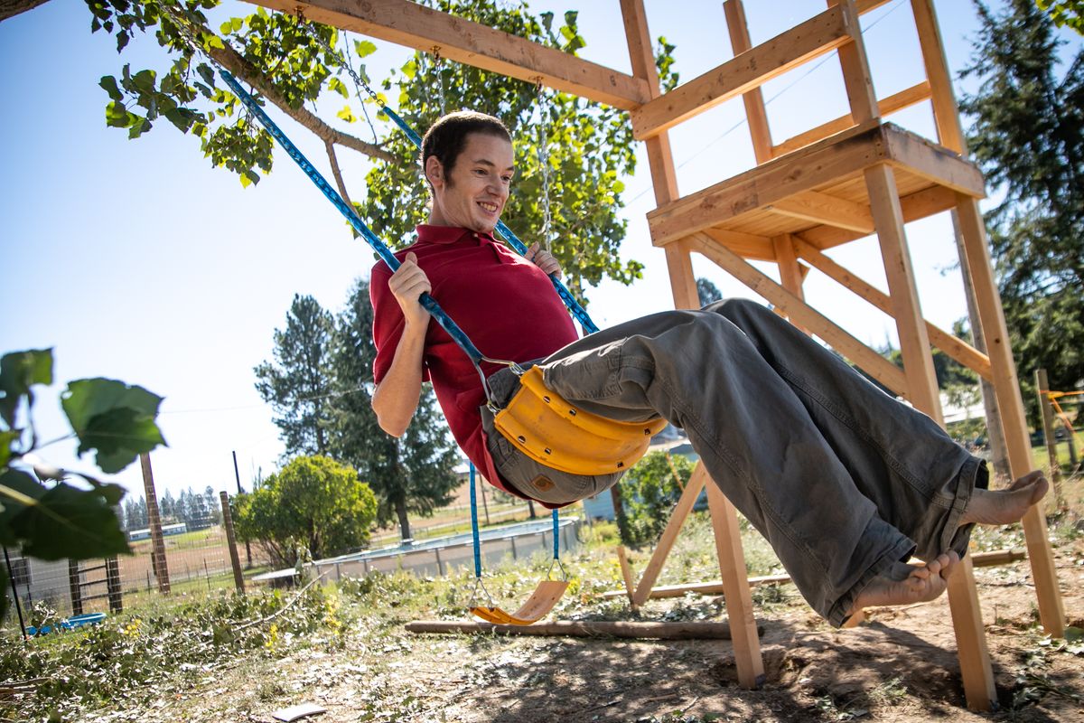 Steven McAdams takes a ride on his new and nearly finished swing set on Sept. 9 at his home in Newman Lake. McAdams, 34, has autism and lives with his sister, Andria McAdams, who also is his caretaker. The set is being built by Tim Tuttle and Ryan Schumacher of T&R Custom Woodwork.  (Libby Kamrowski/The Spokesman-Review)