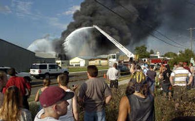 
A crowd gathers to watch as fuel tanks and vehicles burn Monday  at Whitley Fuel at 2733 N. Pittsburg St. Fire raged through the business, sending a huge cloumn of smoke over the city. 
 (Photos by Christopher Anderson / The Spokesman-Review)