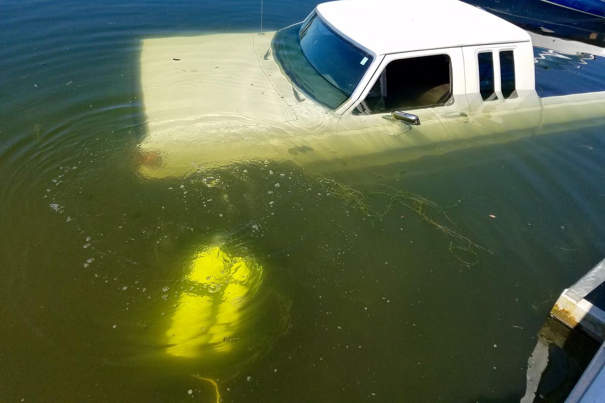 Spokane County Sheriff’s Office diver Deputy Brad Humphrey, wearing yellow air tanks, dives to free a submerged trailer from underneath a dock at Silver Lake on Friday, June 30, 2017. (Spokane County Sheriff’s Office)
