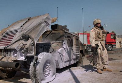 
A U.S. soldier stands next to a damaged military vehicle Thursday in Baqouba, Iraq. A bomb exploded near the vehicle, killing three people and wounding 14. 
 (Associated Press / The Spokesman-Review)