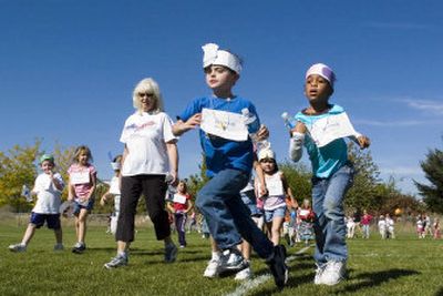 
Adams Elementary students Evan West, 6, center, and Kaitlyn White, 6, right, jog past a group of walkers during the all-school walk-a-thon Thursday. 
 (Joe Barrentine / The Spokesman-Review)