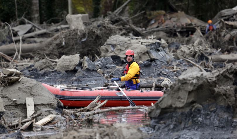A searcher uses a small boat to look through debris from a deadly mudslide Tuesday in Oso, Wash. (Associated Press)