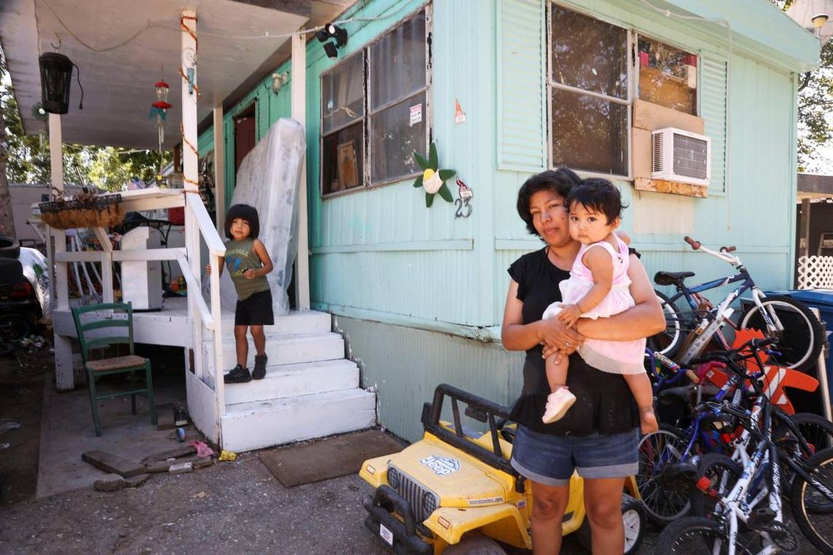 Michelle Price Calderon, holding her 11-month-old daughter Teresa Torres Price, is a full-time mother to her two youngest children. Heusebio Cameron Torres Price, 4, watches from the entrance to their mobile home in a park on West Malad Street in Boise.  (Darin Oswald)