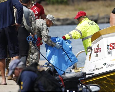 Water safety officials hand over possible debris from an Army UH-60 Black Hawk helicopter crash to military personnel stationed at a command center in a harbor, Wednesday, August 16, 2017 in Haleiwa, HI. An Army helicopter with five on board crashed several miles off Oahu's North Shore late Tuesday. Rescue crews are searching the waters early Wednesday. (Marco Garcia / Associated Press)