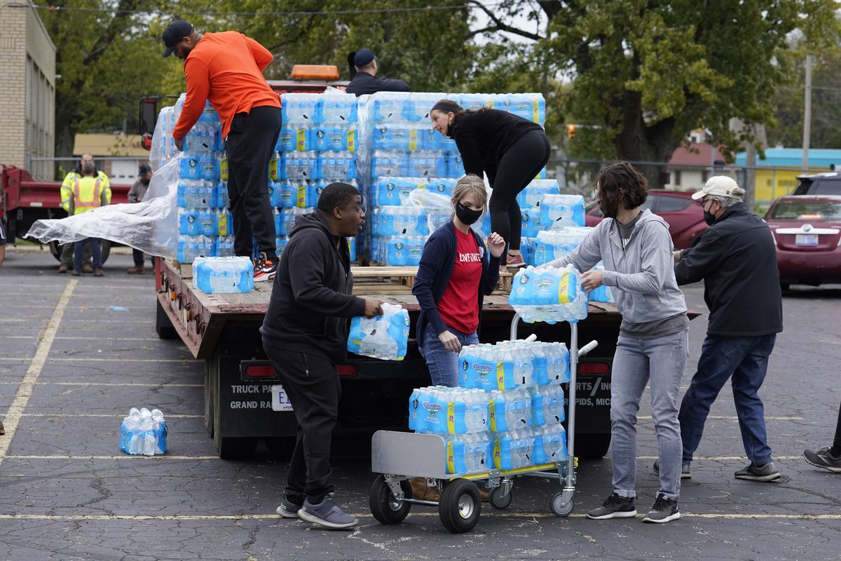Volunteers prepare bottled water to be distributed to residents at the local high school parking lot Thursday, Oct. 21, 2021, in Benton Harbor, Mich. The water system in Benton Harbor has tested for elevated levels of lead for three consecutive years. In response, residents have been told to drink and cook with bottled water and the state has promised to spend millions replacing lead service lines.  (Charles Rex Arbogast)