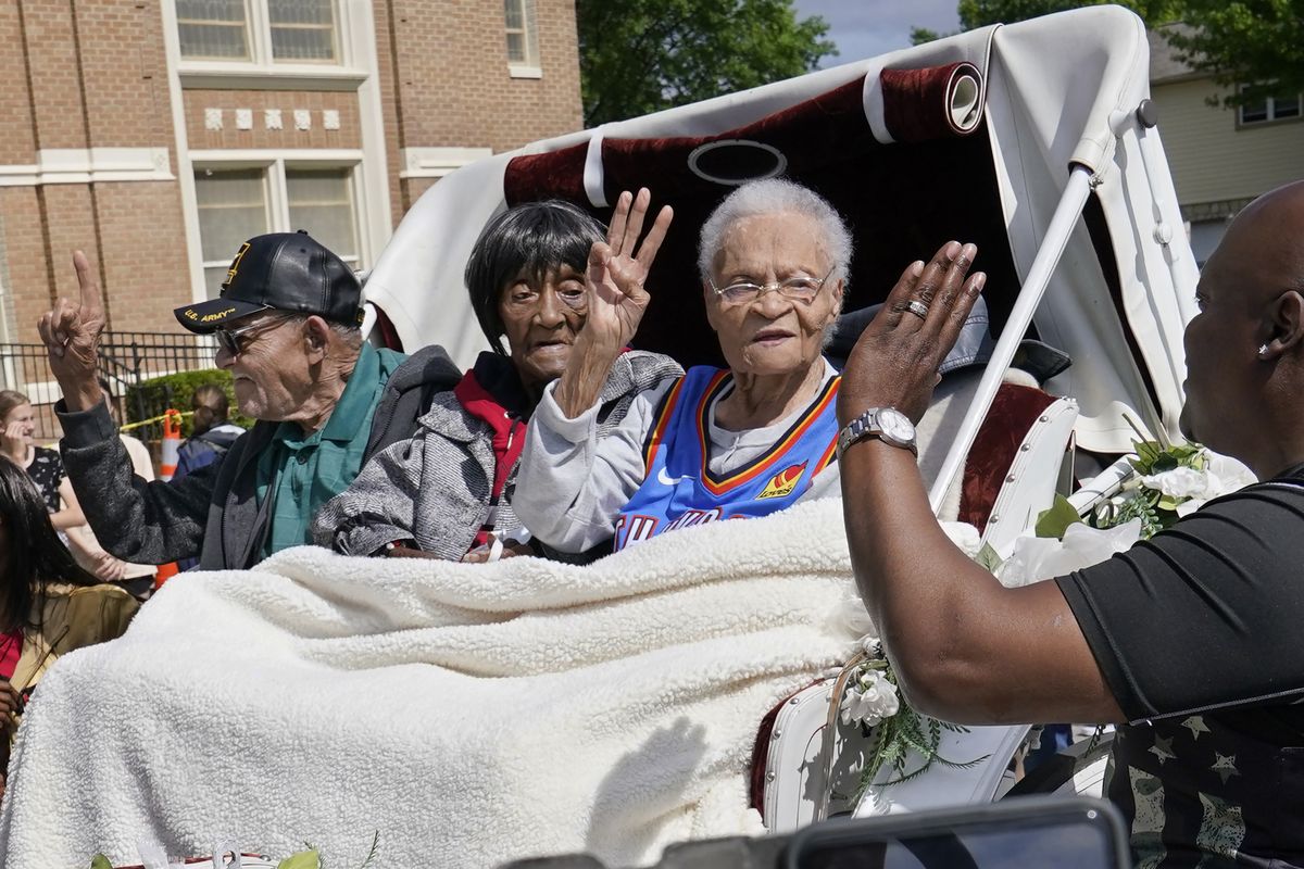 FILE - In this Friday, May 28, 2021 file photo, Tulsa Race Massacre survivors, from left, Hughes Van Ellis Sr., Lessie Benningfield Randle, and Viola Fletcher, wave and high-five supporters from a horse-drawn carriage before a march in Tulsa, Okla. Earlier in the month, the three gave testimony in a panel about the massacre in the U.S. House of Representatives.  (Sue Ogrocki)