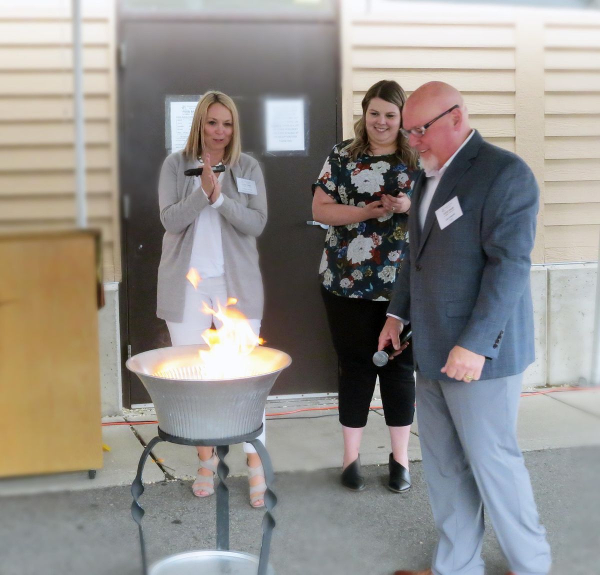 Lindsey Myhre of STCU, Cal Coblentz of Spokane Valley Partners CEO and Lindsey Funderburke of STCU hold a burning ceremony to celebrate the Partners paying off its mortgage contract. (Courtesy of Cal Coblentz)