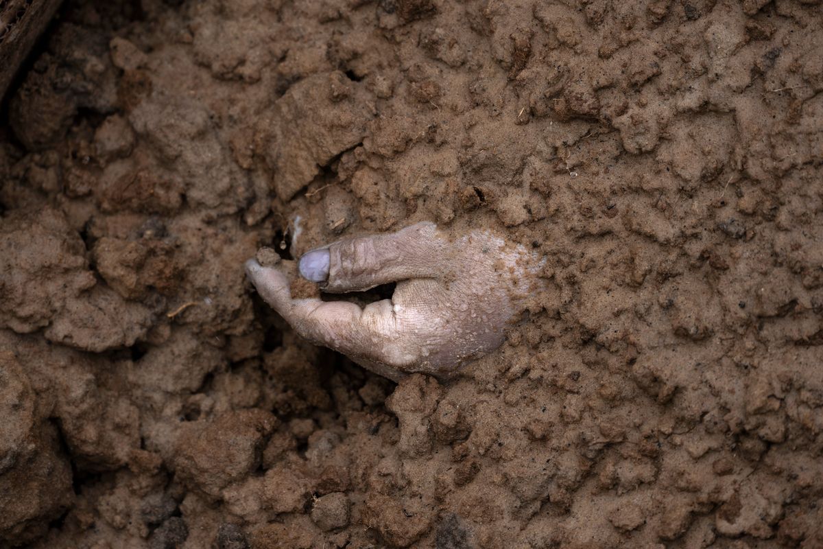 FILE - The hand of a corpse buried along with other bodies is seen in a mass grave in Bucha, in the outskirts of Kyiv, Ukraine, April 3, 2022. Ukrainian leaders have encouraged journalists to document what is happening in the country.  (Rodrigo Abd)