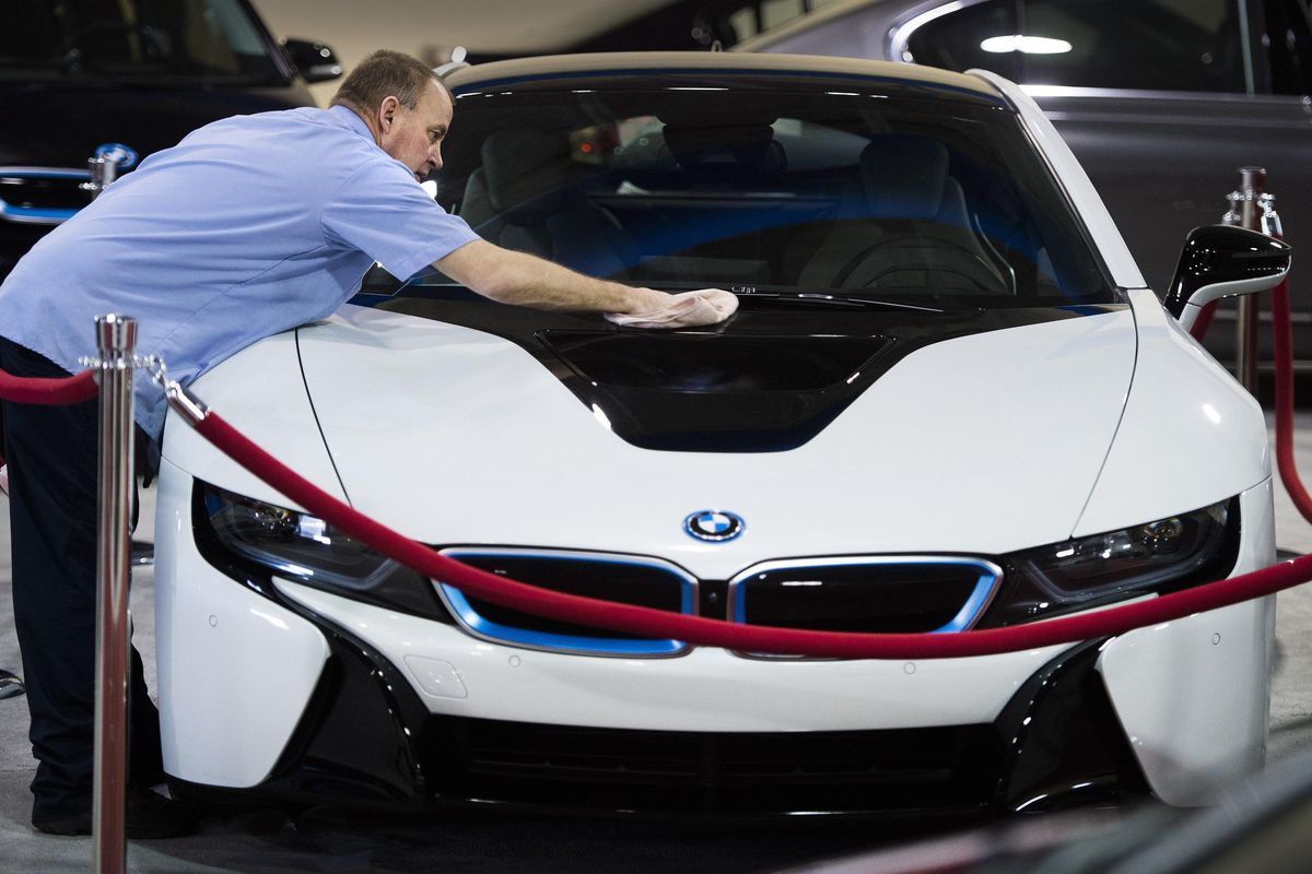 Gary Thomson, an auto detailer for BMW of Spokane, rubs on the showroom wax finish on a BMW i8, Thursday, Feb. 11, 2016, at the Spokane Auto Show at the Spokane County Fair & Expo Center. Sticker price on the hybrid car totaled $150,095. The event will feature new cars from 30 manufactures and runs Friday through Sunday. (Dan Pelle / The Spokesman-Review)