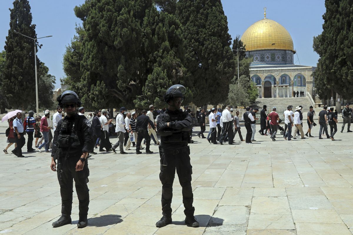 Israeli police officers stand guard as Jewish men visit the Dome of the Rock Mosque in the Al Aqsa Mosque compound, during the annual mourning ritual of Tisha B'Av (the ninth of Av) -- a day of fasting and a memorial day, commemorating the destruction of ancient Jerusalem temples, in the Old City of Jerusalem, Sunday, July 18, 2021.  (Mahmoud Illean)