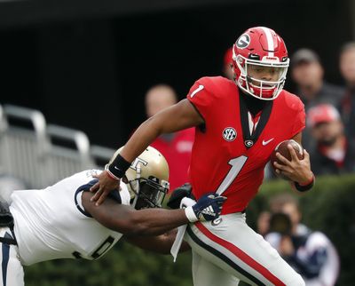 In this Saturday, Nov. 24, 2018,  photo, Georgia quarterback Justin Fields (1) tries to escape from Georgia Tech linebacker Victor Alexander (9) in the second half of an NCAA college football game in Athens, Ga. The NCAA quietly made a big change last year that helped quarterback Shea Patterson play for Michigan and will determine whether Justin Fields is eligible this fall at Ohio State. (John Bazemore / Associated Press)