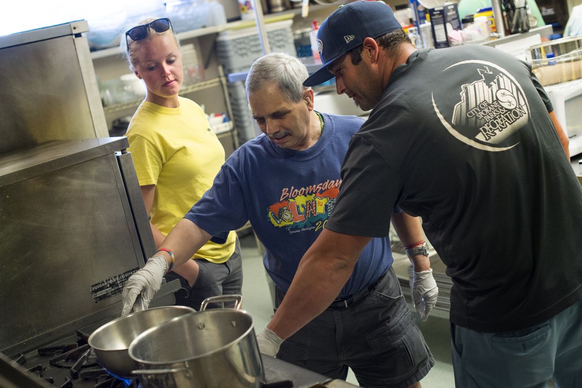 Kayla Clauson, a city employee with Therapeutic Recreation Services, watches as co-worker Patrick McGee helps Tony Juliano place a pan on a burner during a therapeutic cooking class for people with disabilities on Tuesday at Southside Senior and Community Center. The class is among the center’s efforts to attract more people to the facility. (TYLER TJOMSLAND )