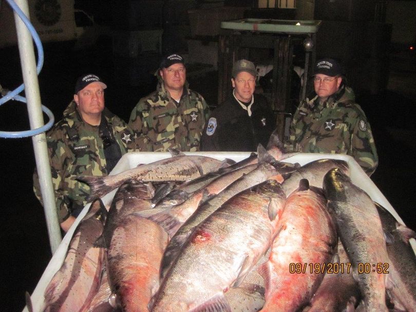 Fish and wildlife officers post by some of the chinook and steelhead confiscated from an illegal gillnetting operation at the Deschutes River in Oregon. (Oregon Troopers)