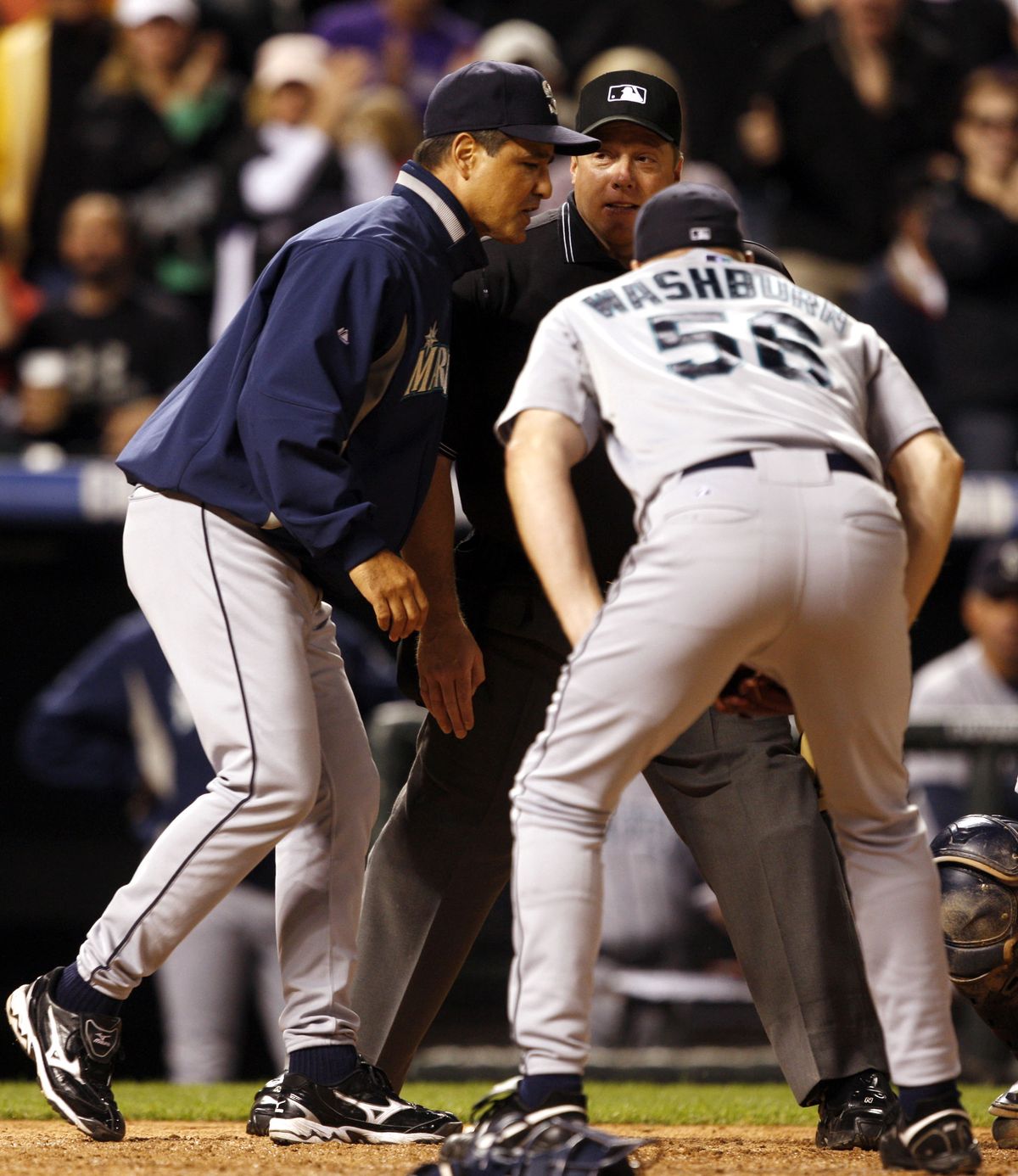 Mariners manager Don Wakamatsu, left, and starting pitcher Jarrod Washburn argue with home-plate umpire Bruce Dreckman after he called Colorado’s Ian Stewart safe at home in the sixth inning of Friday’s game in Denver.  (Associated Press / The Spokesman-Review)