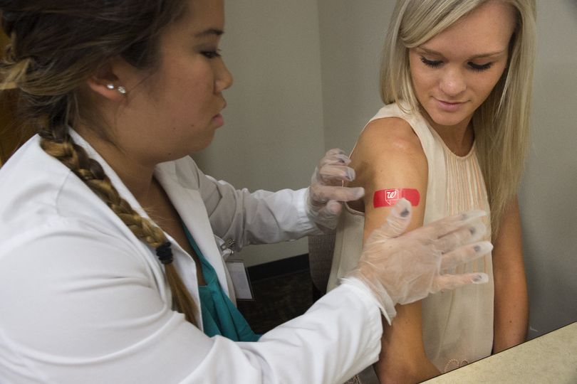 Jessica Shinn, a third-year pharmacy student at WSU Spokane, puts a bandage on nursing student Addie Burkhart after giving her a flu shot during a health fair on Thursday at the Riverpoint campus in downtown Spokane. (Tyler Tjomsland)