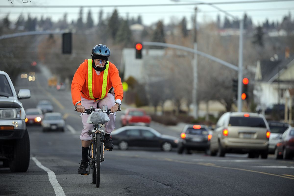 Kim Sherwood, suited up for his bicycle commute, rides south on Post Street on Tuesday. He said he gets funny looks at his bicycling outfit, a misfit collection of warm and  brightly colored clothes and plastic to stay dry on his 31-mile one-way commute. (Jesse Tinsley)