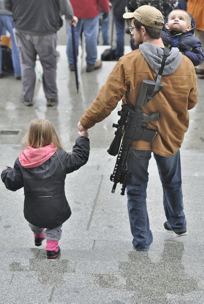 Gun-rights protester Josh McIntyre brings daughter Love, 3, and son Lazarus, 1, along with his semi-automatic rifle, to a 2018 rally on the Capitol steps in Olympia.  (Jim Camden / The Spokesman-Review)