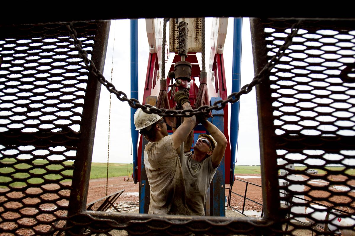 Austin Mitchell, left, and Ryan Lehto work on an oil derrick. New drilling technology has freed up vast reserves of oil in western North Dakota, fueling an economic bonanza. (Associated Press)