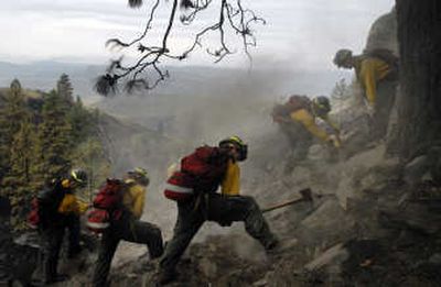 Fire crews from Dust Busters Plus, a private fire contractor, mop up hot spots from the Tunk Grade fire along the McLoughlin Canyon on Wednesday.
 (Jed Conklin / The Spokesman-Review)