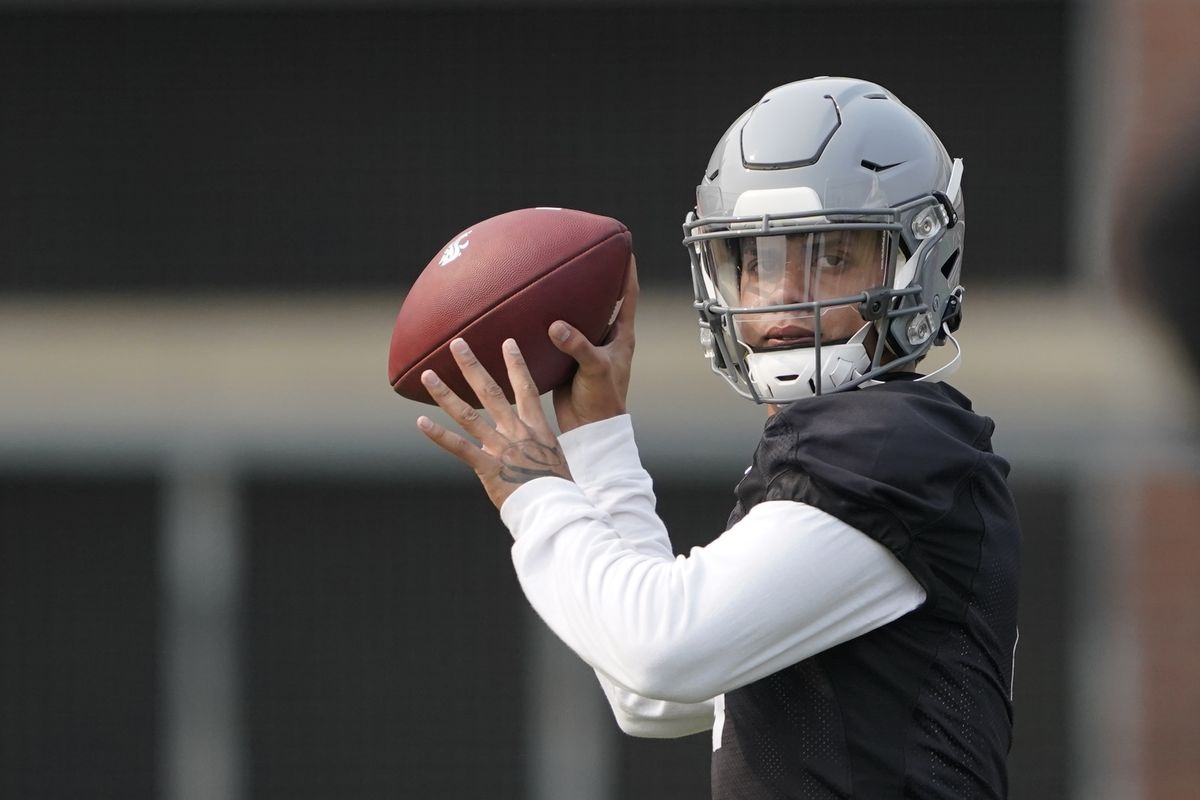 Washington State’s Jayden de Laura, scanning the field, is locked in a battle with Jarrett Guarantano to be first-string quarterback.  (Associated Press)