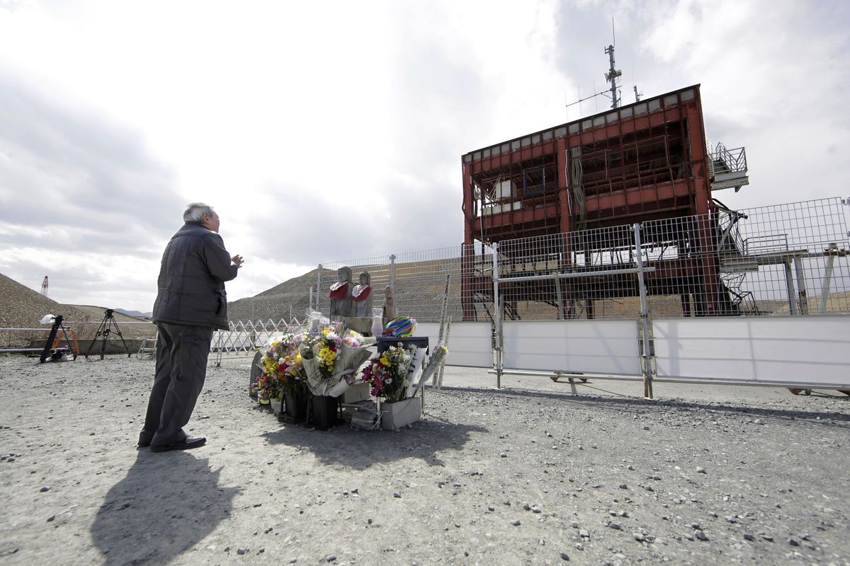 A man prays in front of the skeletal remains of the former disaster prevention center in Minamisanriku, Miyagi prefecture, northern Japan Friday, March 11, 2016, the fifth anniversary of the 2011 tsunami. (Yusuke Ogata / Kyodo News via Associated Press)