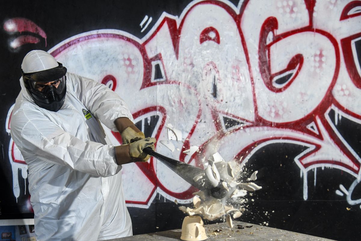 Dan Williams takes a might swing with a baseball bat and smashes stacked ceramic ware, Monday, April 23, 2018, at Rage Spokane. (Dan Pelle / The Spokesman-Review)