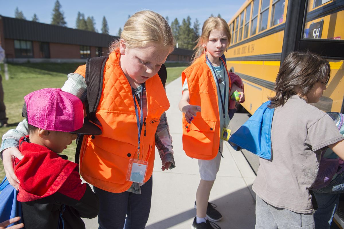 Fifth-grader Annabelle Howes, second from left, a bus helper, makes sure that the last kindergartener makes it on to her bus before the older kids get on Tuesday, April 24, 2018 at Camp Shiloh, the temporary home of Shiloh Hills Elementary in the Mead School District. The bus helper program enlists upper class members to help get kids on the bus because the relocated school how puts most students on the bus instead of them walking home. (Jesse Tinsley / The Spokesman-Review)