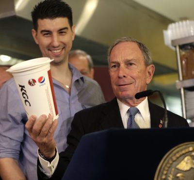 New York City Mayor Michael Bloomberg looks at a 64-ounce cup, as Lucky’s Cafe owner Greg Anagnostopoulos, left, stands behind him in March. An appeals court ruled Tuesday that New York City's Board of Health exceeded its legal authority and acted unconstitutionally when it tried to put a size limit on soft drinks served in city restaurants. (Associated Press)