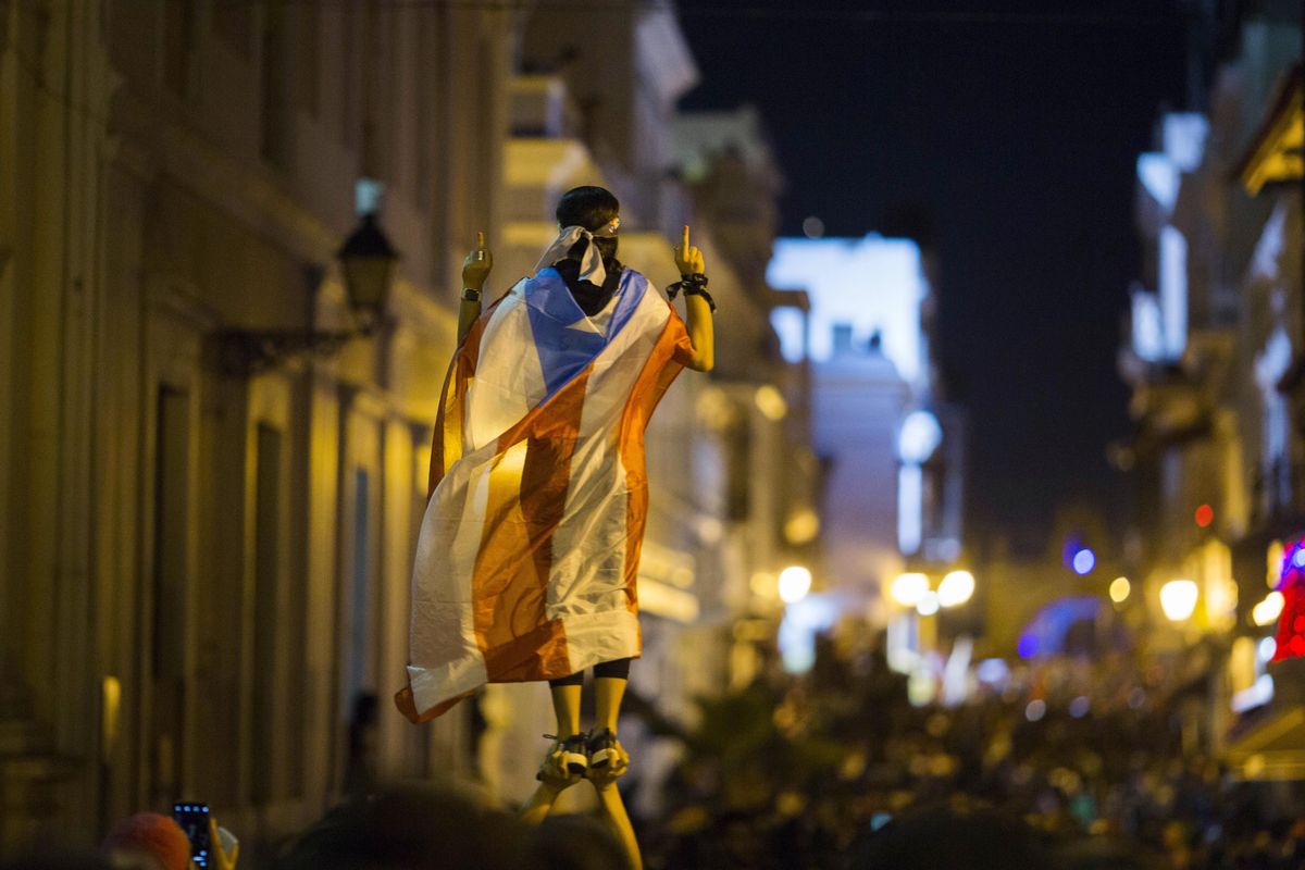 A demonstrator with a Puerto Rican flag reacts during clashes in San Juan, Puerto Rico, on Wednesday. Thousands of people marched to the governor’s residence in San Juan on Wednesday chanting demands for Gov. Ricardo Rossello to resign after the leak of online chats that show him making misogynistic slurs and mocking his constituents. (Dennis M. Rivera Pichardo / Associated Press)