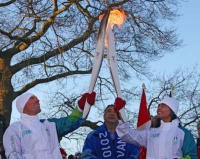 Former Olympic downhill skier Phil Mahre, left, passes the Olympic flame to Canadian torchbearer Chamila Anthonypillai on the Canadian side of the U.S.-Canadian border at Peace Arch Park on Tuesday morning, Feb. 9, 2010. (Associated Press)