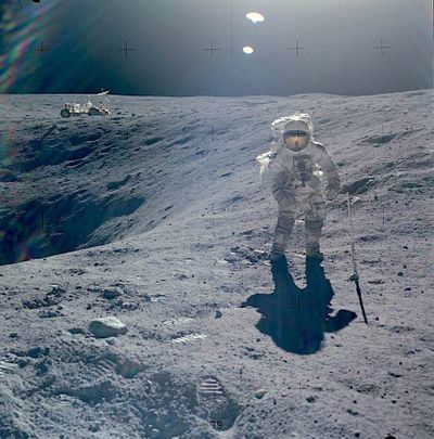 Apollo 16 astronaut Charlie Duke stands beside the moon’s Plum Crater during an outing in the Lunar Rover (in the background) on the lunar surface on April 21, 1972.  (Courtesy of NASA)