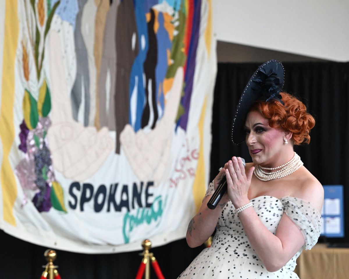 At the recently opened LGBTQ+ heritage display at the Pavilion in Riverfront Park in Spokane, Washington, shown Tuesday, June 4, 2024, drag performer Crystal Marché speaks the small gathering. Behind are memorial quilts and in the collection are gowns and accessories used by drag performers of the past.  (Jesse Tinsley/The Spokesman-Review)
