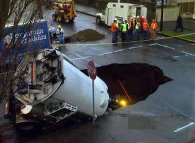 
A city of Portland truck falls into a sinkhole Tuesday injuring two workers. 
 (Associated Press / The Spokesman-Review)