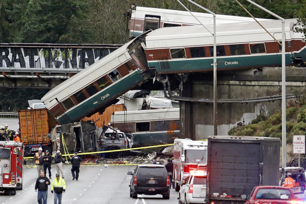 Cars from an Amtrak train lay spilled onto Interstate 5 below alongside smashed vehicles as some train cars remain on the tracks above Monday, Dec. 18, 2017, near DuPont, Wash. The Amtrak train making the first-ever run along a faster new route hurtled off the overpass Monday near Tacoma and spilled some of its cars onto the highway below, killing some people, authorities said. Seventy-eight passengers and five crew members were aboard when the train moving at more than 80 mph derailed about 40 miles south of Seattle before 8 a.m., Amtrak said. (Elaine Thompson / Associated Press)