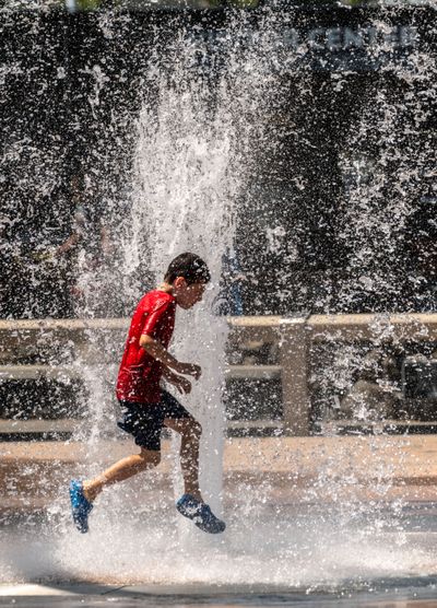 As temperatures hover just above 100 degrees, Joey Daroszewski, 7, races through the water spray of the Rotary Fountain in Riverfront Park on July 29, 2022. Daroszewski and his parents were visiting Spokane from Chicago and were checking out the sights in downtown. Tuesday’s temperatures are expected to hit a high of 99. (COLIN MULVANY/THE SPOKESMAN-REVIEW)