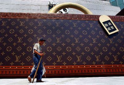 
A scavenger walks past a big luggage-like advertisement of Louis Vuitton at the boutique under the direct management of Louis Vuitton in Shanghai. 
 (Associated Press / The Spokesman-Review)