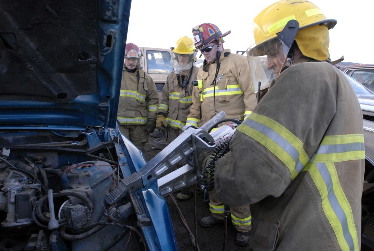 Spokane Valley firefighter David Baird, right, practices removing a fender with an Amkus spreader. Looking on are, from left, Capt. Terry Gese, firefighter Tom Carleton and Capt. Ryan Lieuallen. The four took part in vehicle extrication classes at Spalding’s Pull and Save wrecking yard Nov. 5.  (Photos by J. BART RAYNIAK / The Spokesman-Review)