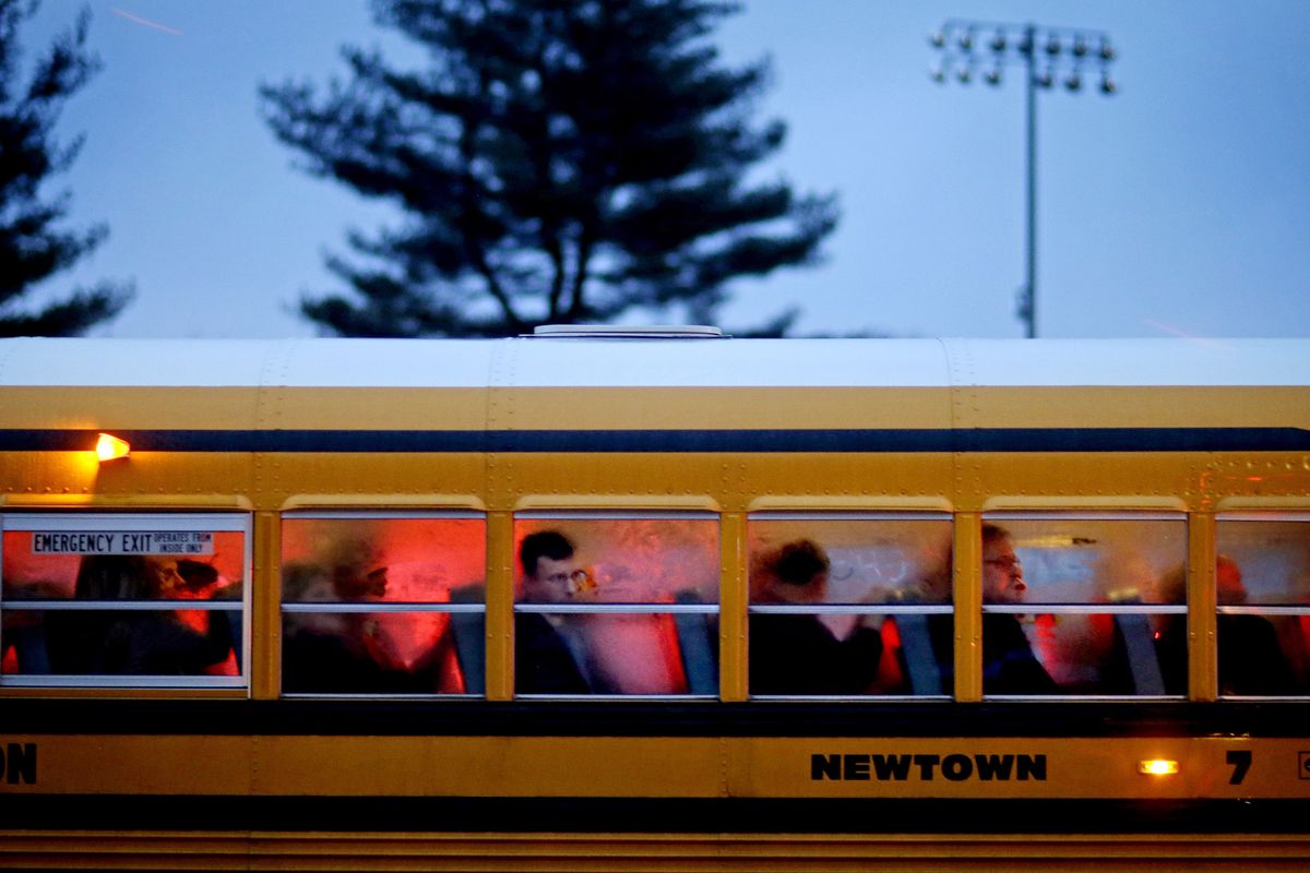People arrive on a school bus at Newtown High School for a memorial vigil attended by President Barack Obama for the victims of the Sandy Hook Elementary School shooting, Sunday, Dec. 16, 2012, in Newtown, Conn. A gunman walked into Sandy Hook Elementary School in Newtown Friday and opened fire, killing 26 people, including 20 children. (David Goldman / Associated Press)
