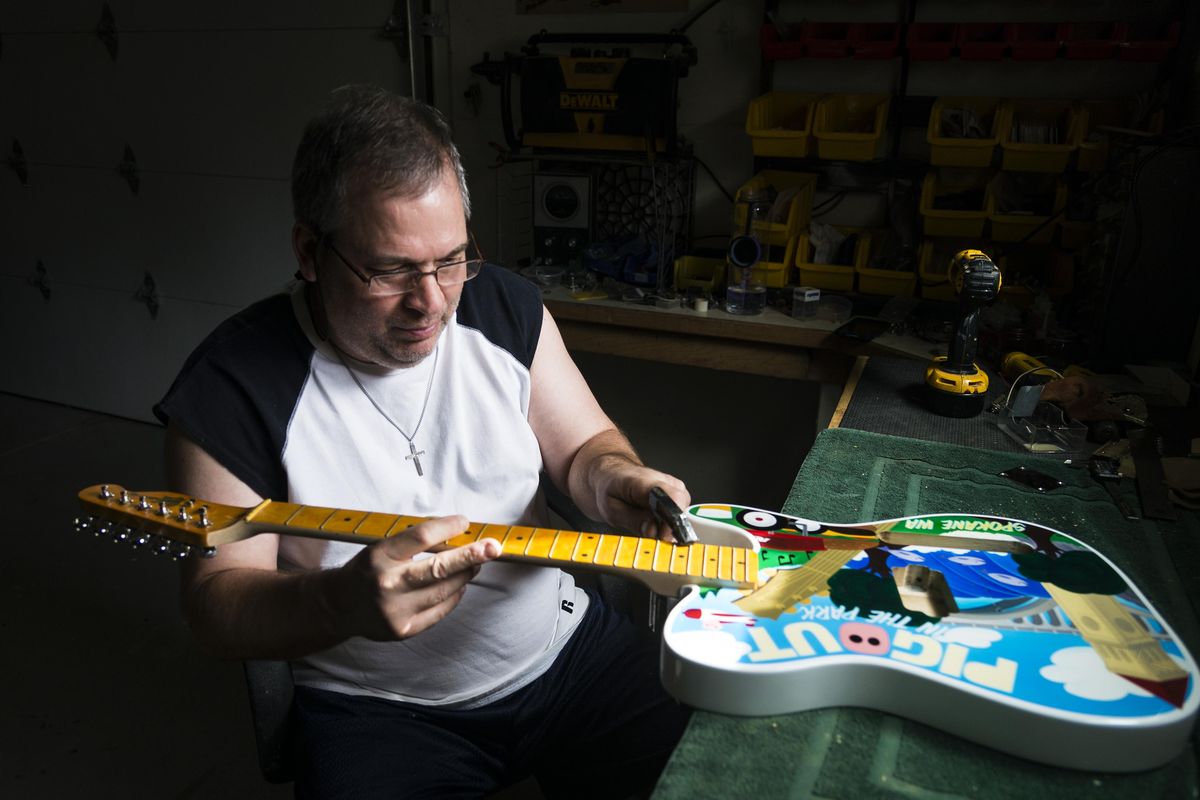 Patrick Coleman, of Lynn Ellsworth Guitars in  Spokane Valley, puts the finishing touches on a colorful custom-made Pig Out guitar for Bill Burke, who started and organizes Pig Out in the Park. Coleman presented the guitar to Burke at the Riverfront park IMAX stage Friday when Burke’s band Yellow Dog took the stage. (Colin Mulvany / The Spokesman-Review)