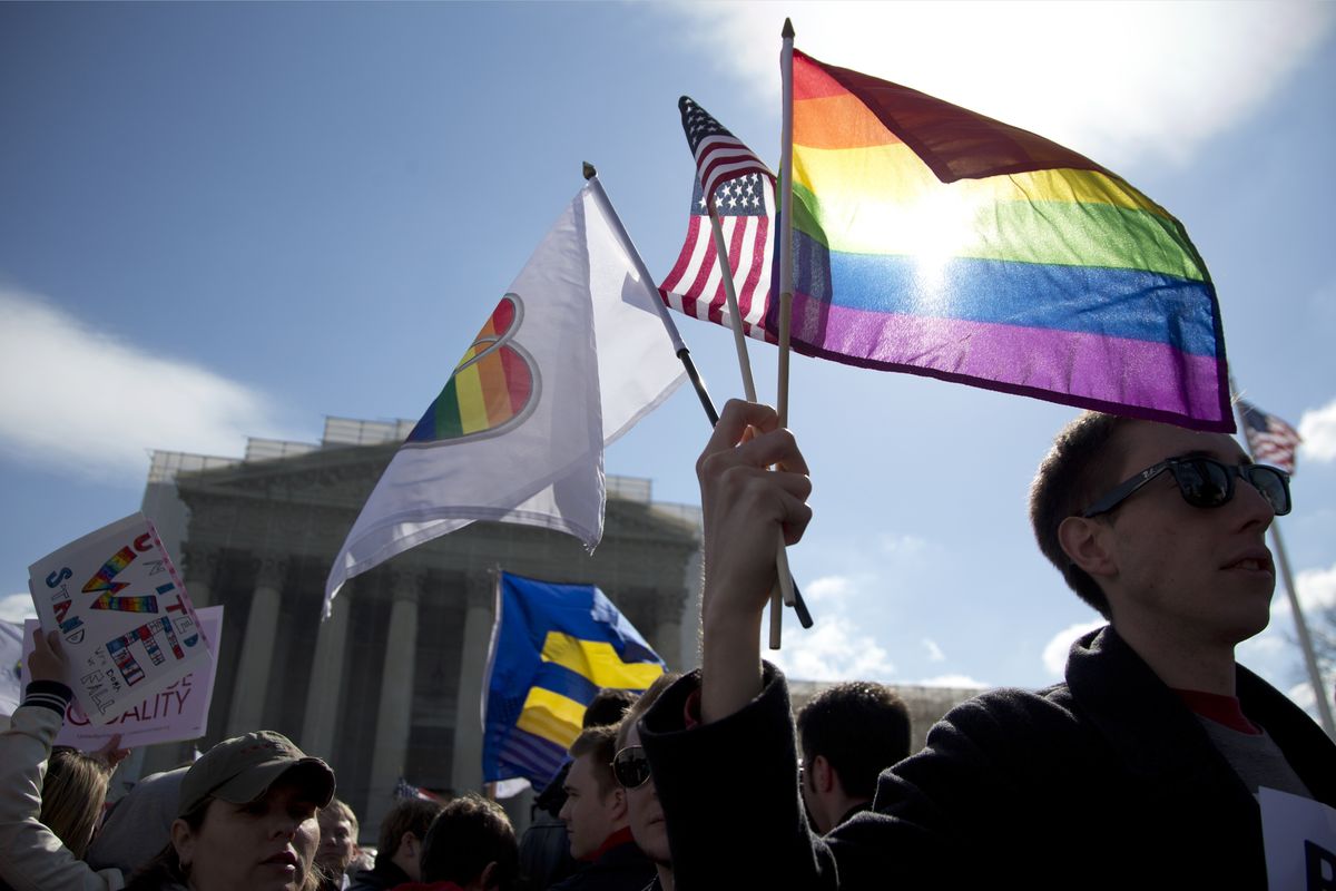 Kevin Coyne holds flags in front of the Supreme Court in Washington Wednesday, the second day of gay marriage cases. (Associated Press)