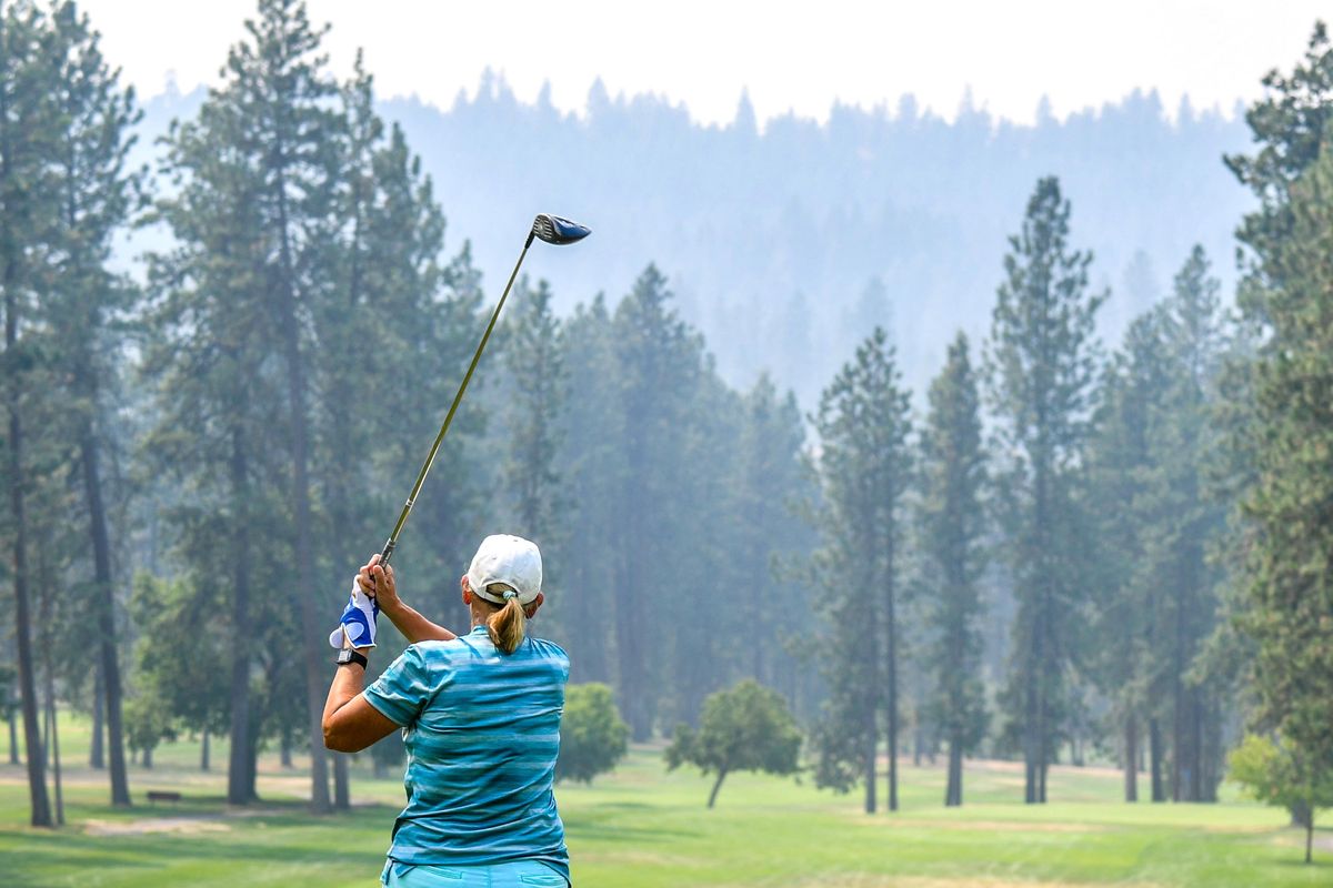 Carol Lampard, of Newman Lake, launches her ball from the 10th tee at Downriver Golf Course and into the wildfire smoke Tuesday. Lampard said the smoke was much worse in Newman Lake.  (DAN PELLE/THE SPOKESMAN-REVIEW)