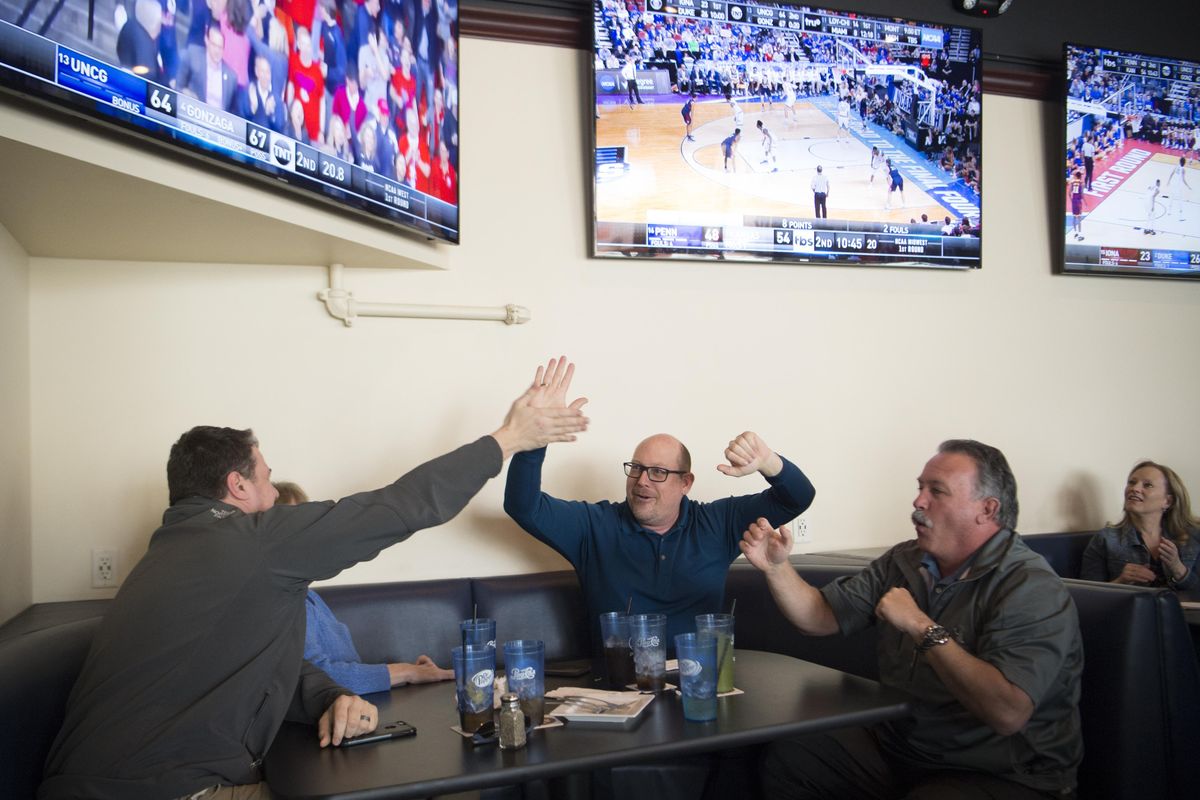 Paul Votava, center, high-fives Leonard Warren, left, while Joe Waits pumps his fists as a 3-point basket falls for the Gonzaga Bulldogs with 20 seconds left in the NCAA Tournament game, which they were watching at 24 Taps Burgers and Brews in Spokane on Thursday. The Zags escaped with a win over UNC Greensboro, 68-64. (Jesse Tinsley / The Spokesman-Review)