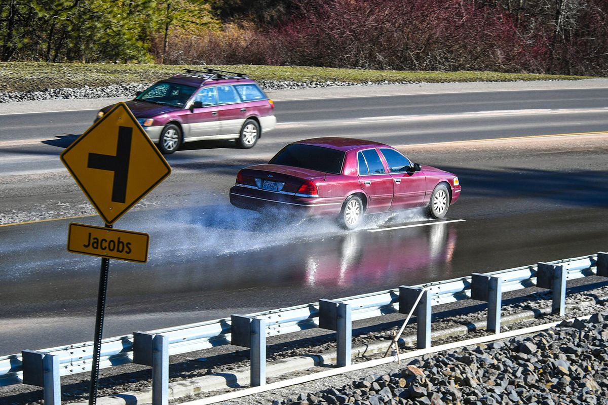 A Ford Crown Victoria splashes through water from a natural spring leaking through the asphalt near the Bigelow Gulch-Forker Road interchange on Wednesday leading to ice on the road and dangerous conditions.  (Dan Pelle/THESPOKESMAN-REVIEW)